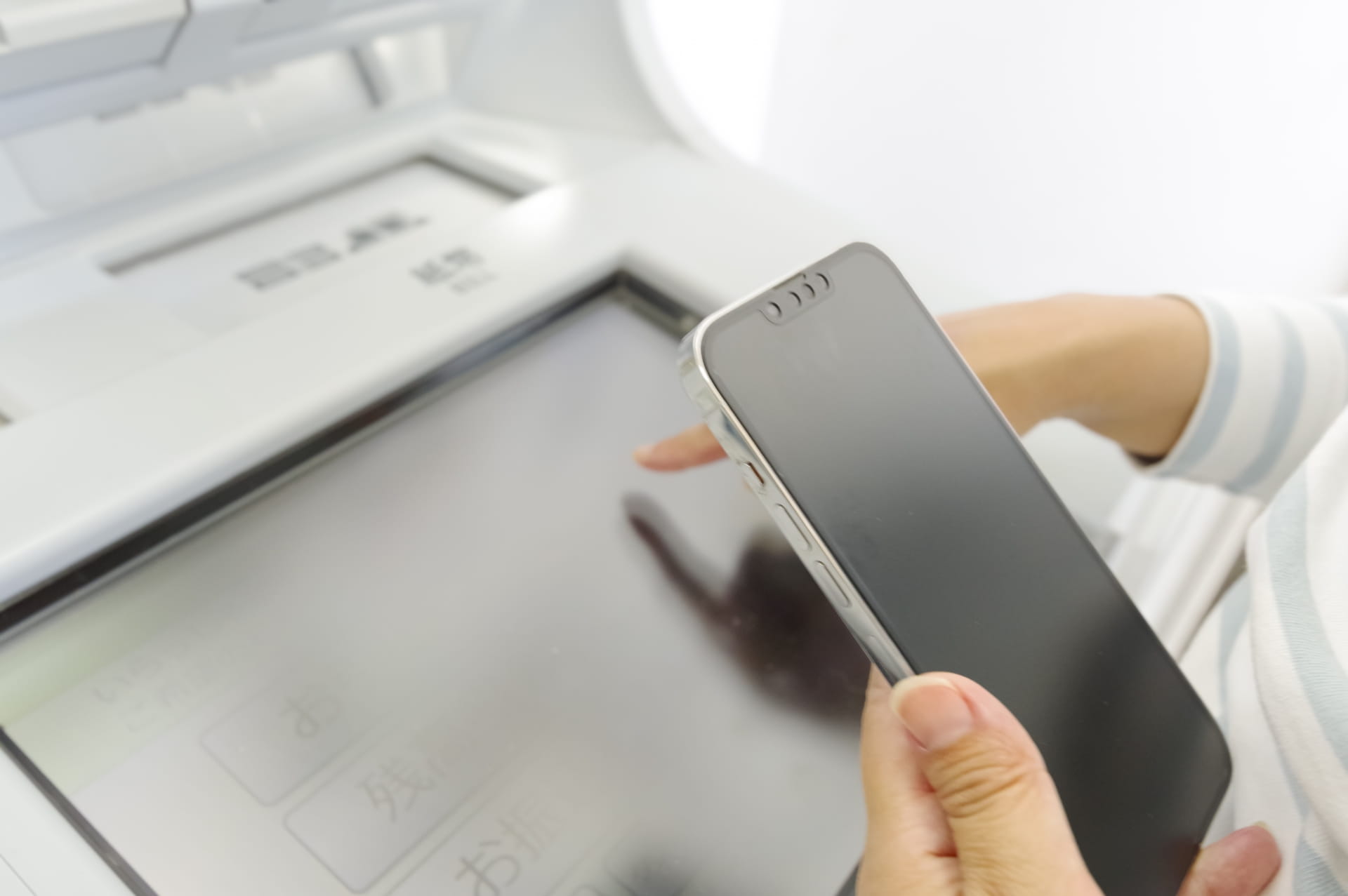 スマートフォンの画面を確認しながら振込手続きを行っている様子