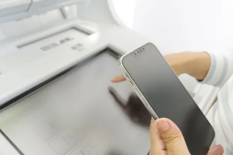 スマートフォンの画面を確認しながら振込手続きを行っている様子