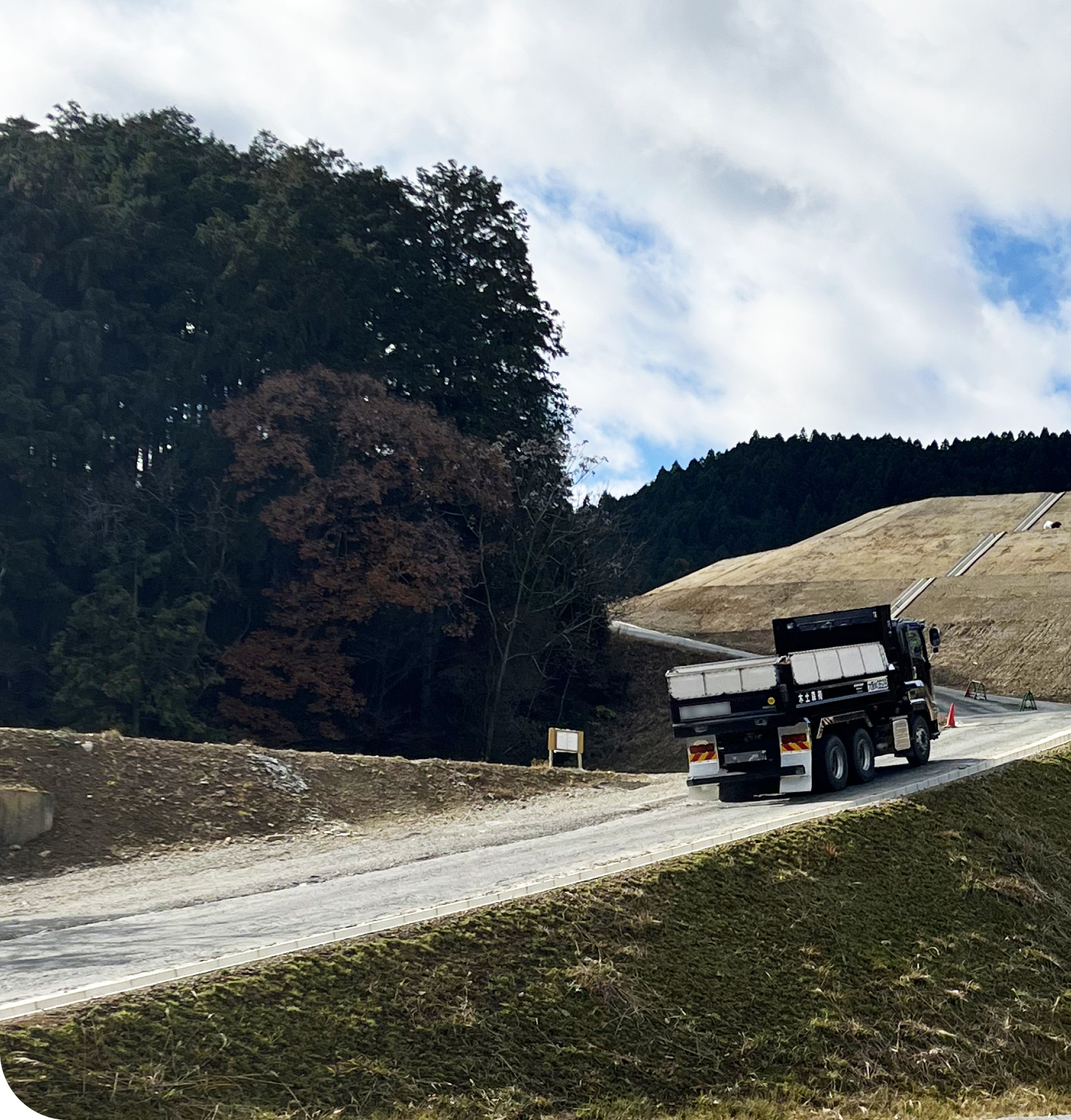 山林と造成地の間を走るトラックの風景