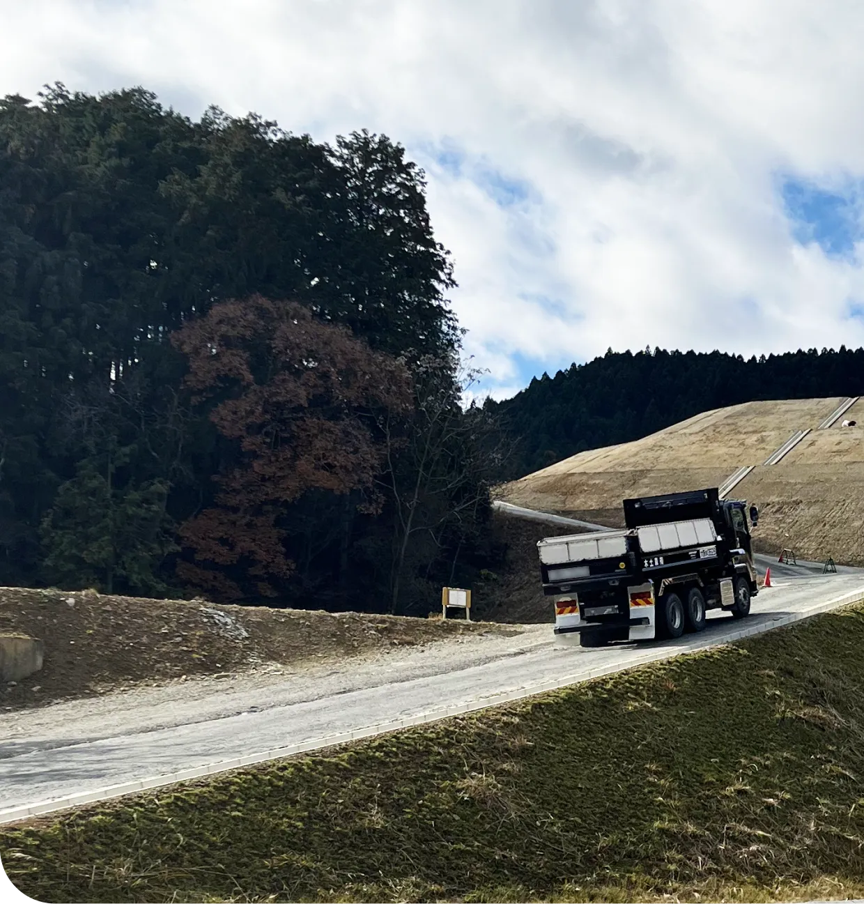 山林と造成地の間を走るトラックの風景
