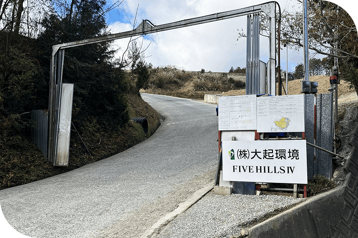 山道の入口にあるゲートとFIVE HILLS IV大起環境と記載された看板が立つ工事現場