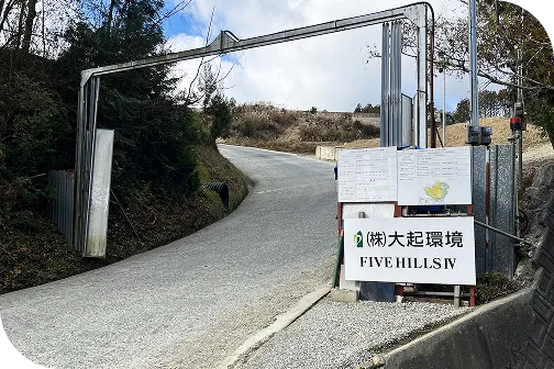 山道の入口にあるゲートとFIVE HILLS IV大起環境と記載された看板が立つ工事現場