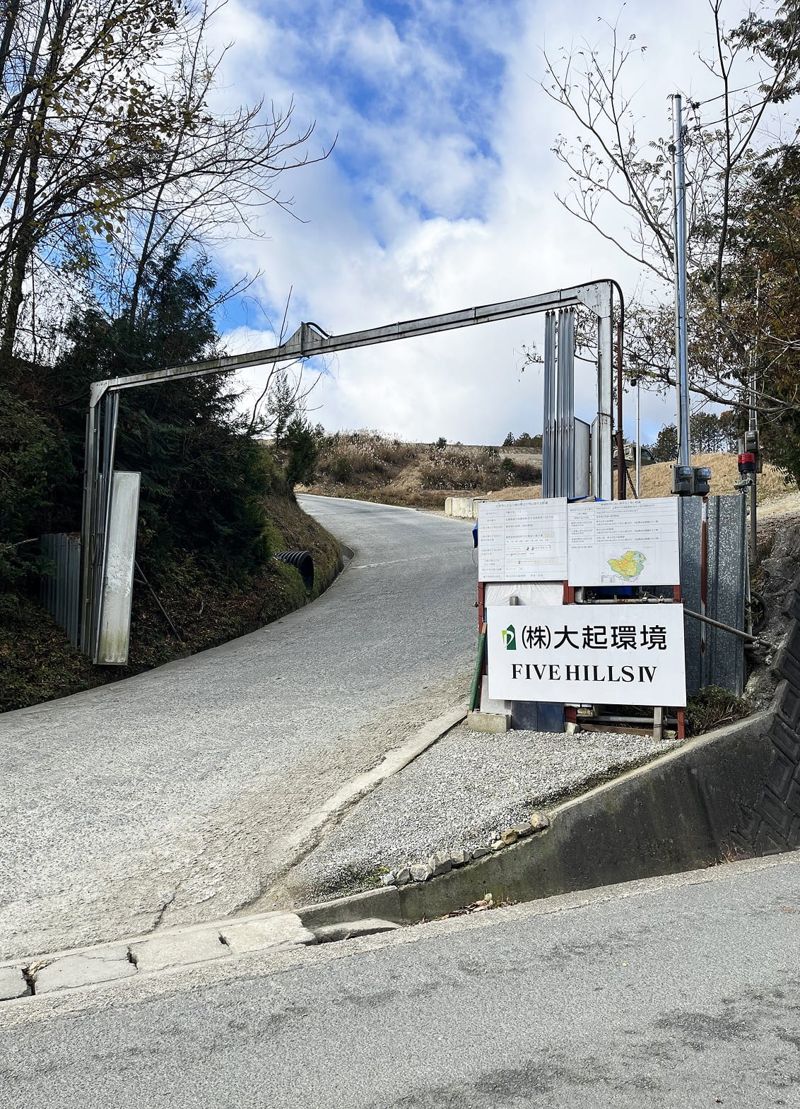 山道の入口にあるゲートとFIVE HILLS IV大起環境と記載された看板が立つ工事現場