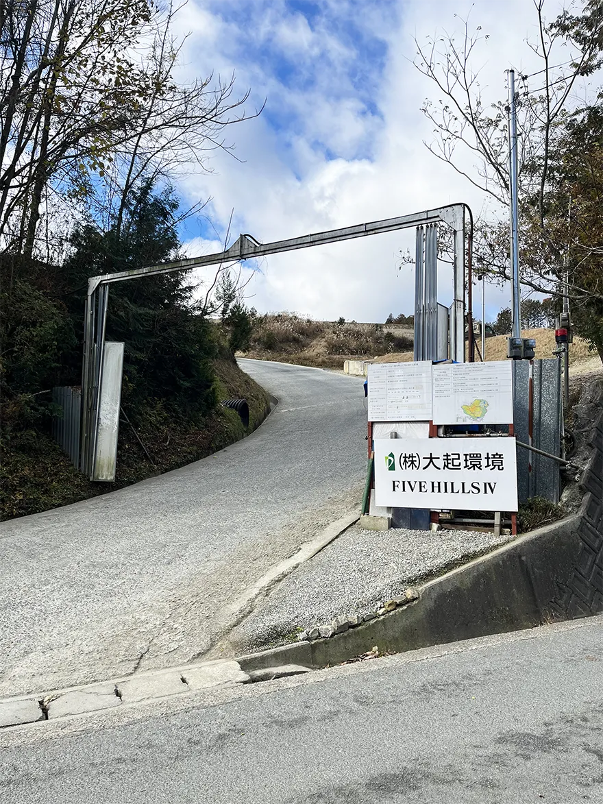 山道の入口にあるゲートとFIVE HILLS IV大起環境と記載された看板が立つ工事現場